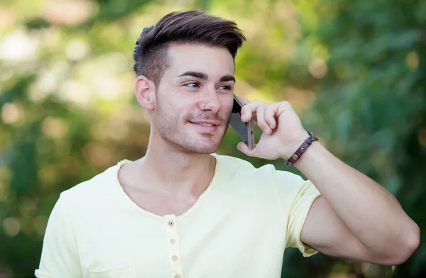 Attraktiv man med mobiltelefon i parken — Stockfoto