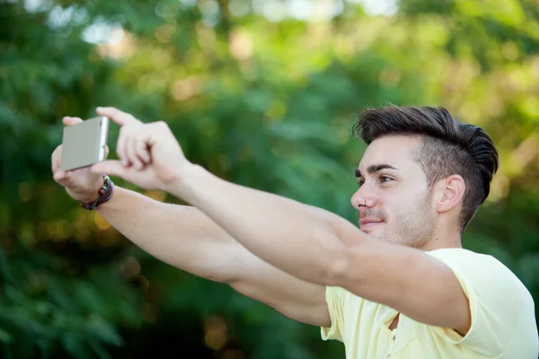 Attractive man with mobile phone in the park — Stock Photo, Image