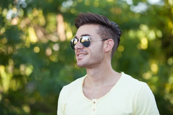 Tipo atractivo en el parque con gafas de sol — Foto de Stock