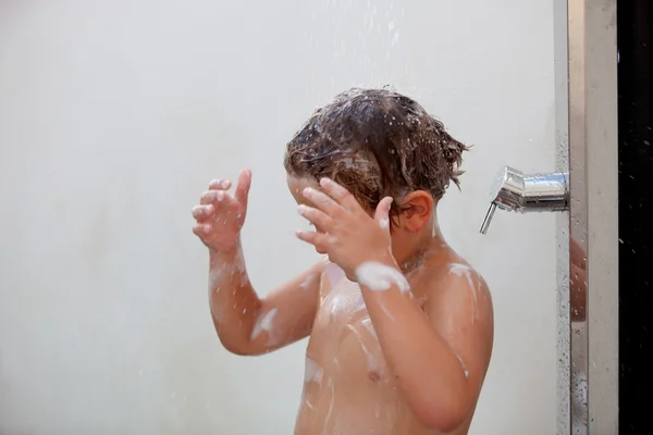 Смешной ребенок принимает душ во дворе — стоковое фото