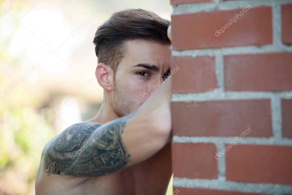 fit athletic man leaning against a brick wall