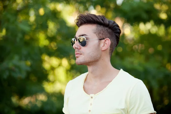 Attraktiv kille i parken med solglasögon — Stockfoto