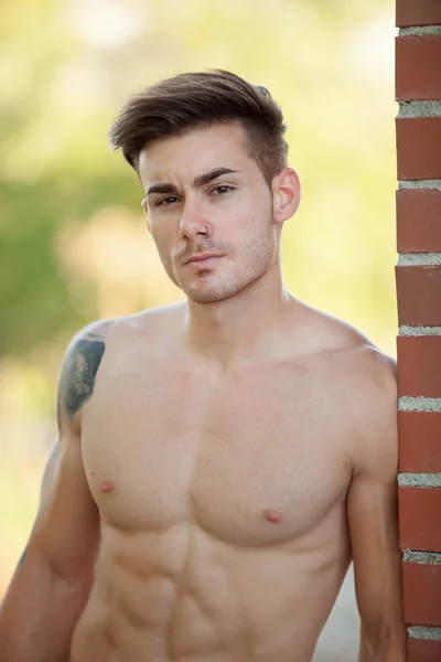 Fit athletic man leaning against a brick wall — Stock Photo, Image