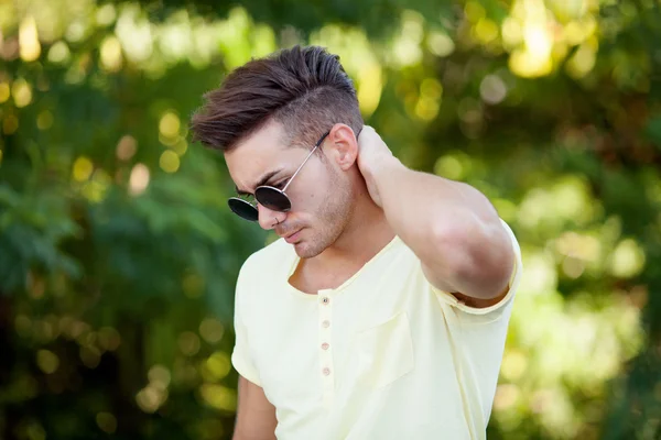Atraktivní chlapík v parku se slunečními brýlemi — Stock fotografie