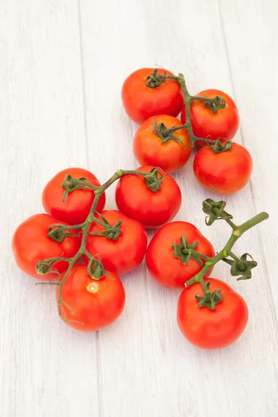 Tomates sobre um fundo de madeira branco — Fotografia de Stock