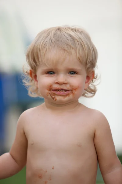 Happy baby with a dirty face after eat chocolate — Stock Photo, Image