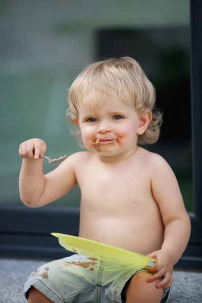 Menino feliz comer bolo de chocolate — Fotografia de Stock