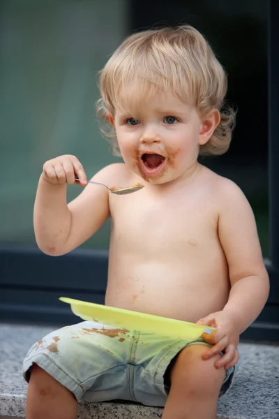 Menino feliz comer bolo de chocolate — Fotografia de Stock