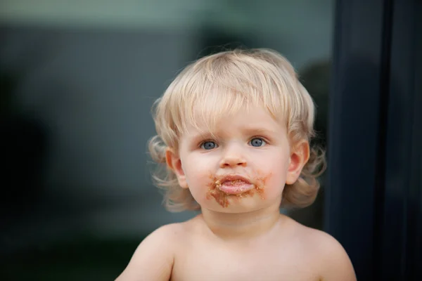 Happy baby with a dirty face after eat chocolate — Stock Photo, Image
