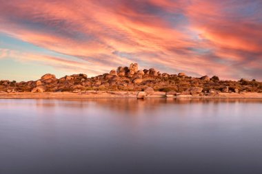 Bir gölün kıyısında turuncu gökyüzü ile güzel bir gün batımı