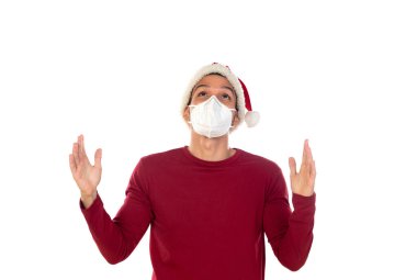 Beyaz bir arka planda izole edilmiş, Noel şapkalı ve maskeli Afrikalı bir adam.