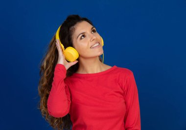 Beyaz arka planda izole edilmiş müzik dinleyen kıvırcık saçlı ve kulaklıklı güzel beyaz bir kızın portresi.