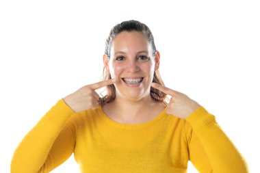 Diş teli takan, sarı bir forma giyen, beyaz bir arka planda izole edilmiş yetişkin bir kadın.