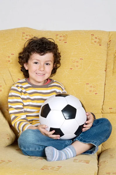 Lindo Niño Con Una Pelota Fútbol Sofá Casa —  Fotos de Stock