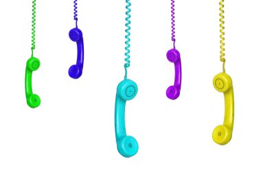 Beyaz arka planda izole edilmiş pek çok renkli eski telefon asılı.