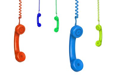 Beyaz arka planda izole edilmiş pek çok renkli eski telefon asılı.