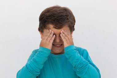 Mavi gözlü güzel bir çocuk beyaz bir arka planda el kol geziyor.