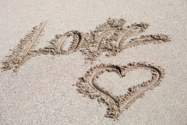 Love written on the sand with a hearth drawing — Stock Photo, Image