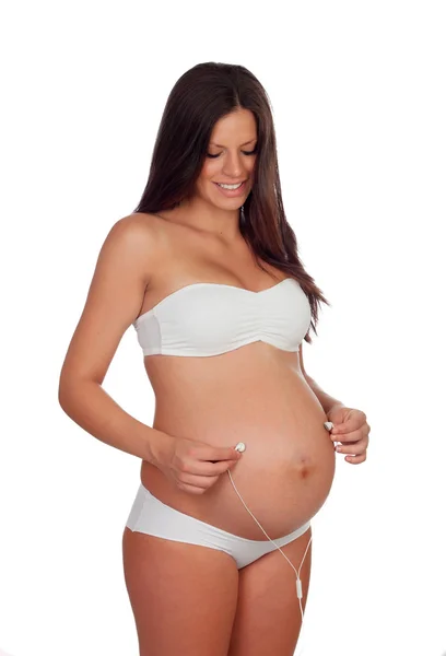 Pregnant woman putting headphones on her belly — Stock Photo, Image