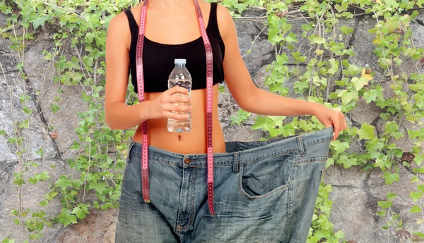 Thin woman stuck in huge pants — Stock Photo, Image