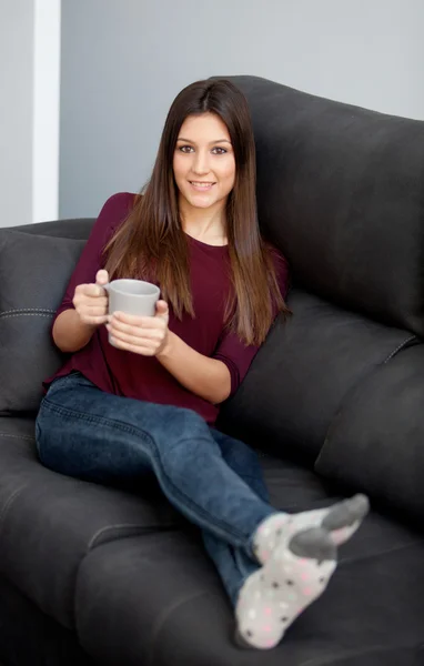 Jong meisje liggend op de Bank het drinken van thee — Stockfoto