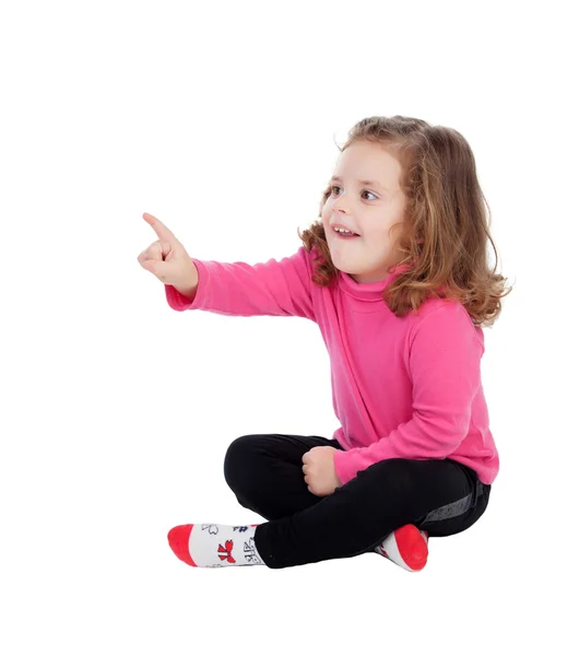 Cute little girl sitting on the floor pointing something with th — Stock Photo, Image