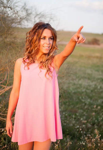 Beautiful young woman indicating something in the countryside — Stock Photo, Image