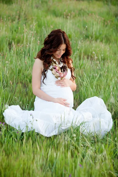 Relaxed pregnant woman sitting on the grass — Stock Photo, Image