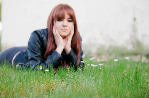 Rebellious teenager girl with red hair lying on the grass — Stock Photo, Image