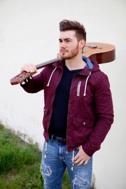 Yakışıklı adam bir gitar onun omuzlarında taşıyan