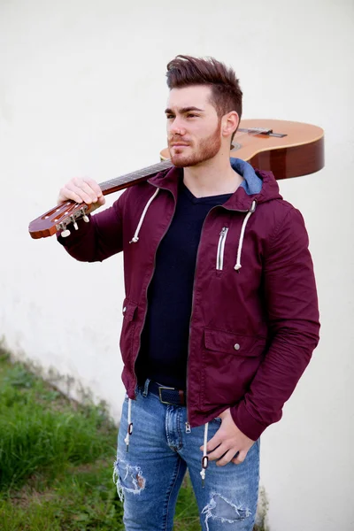 Handsome man carrying a guitar on his shoulders — Stock Photo, Image