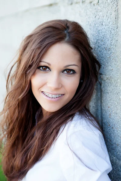 Brunette girl with brackets resting on a wall — Stock Photo, Image