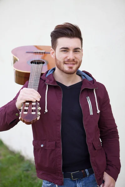 Hombre guapo llevando una guitarra en sus hombros — Foto de Stock