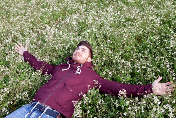 Jovem deitado em um campo de flores — Fotografia de Stock