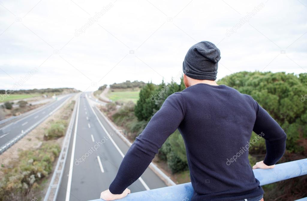 Man back at the top of a bridge over a highway