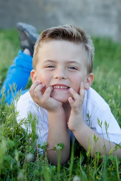 Nadenkend kind liggen op het gras — Stockfoto