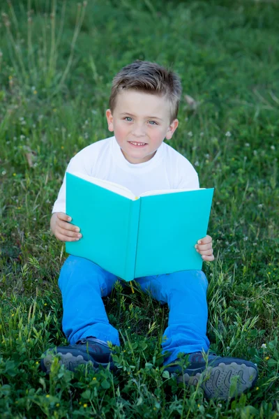 Liten unge läser en bok på utanför — Stockfoto