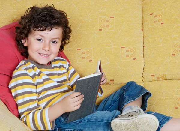 Junge liest Buch auf Sofa — Stockfoto