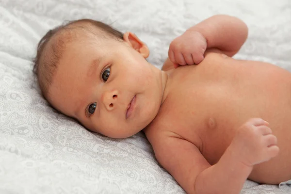 Beautiful baby girl with open eyes lying on sofa — Stock Photo, Image