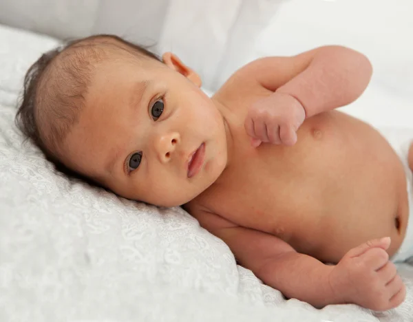 Beautiful baby girl with open eyes lying on sofa — Stock Photo, Image