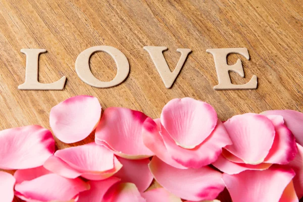 Růžové okvětní lístky s slovo láska — Stock fotografie