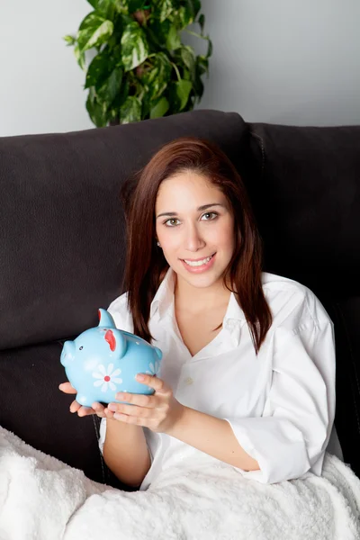 Young woman on couch with a piggy bank — Stock Photo, Image