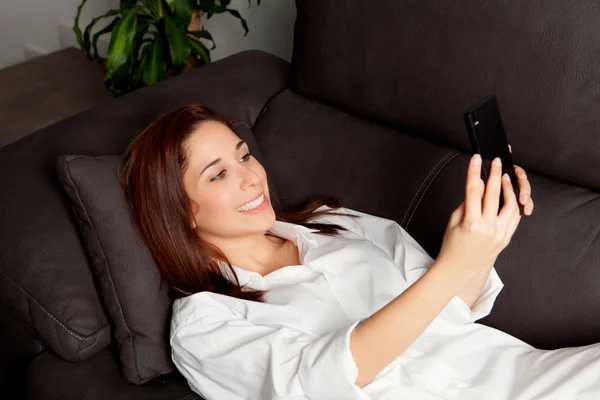 Jeune femme avec le téléphone portable à la maison — Photo