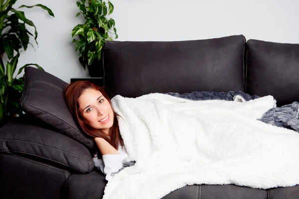 Junges Mädchen liegt auf der Couch, bedeckt mit einer Decke — Stockfoto