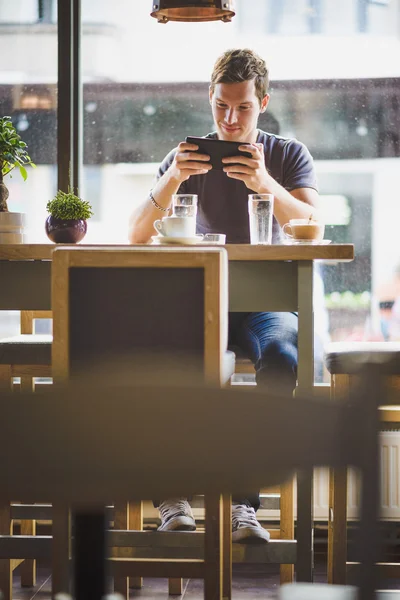 Ung man tittar på tavlan i café — Stockfoto