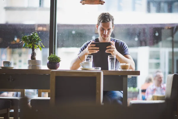 Ung man tittar på tavlan i café — Stockfoto