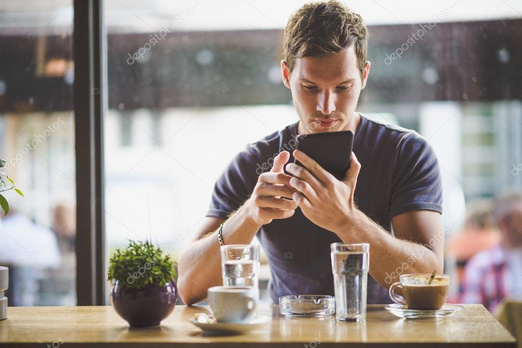 Young man watching tablet in cafe