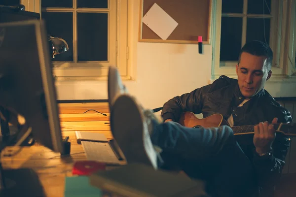 Man spelar gitarr hemma efter jobbet — Stockfoto