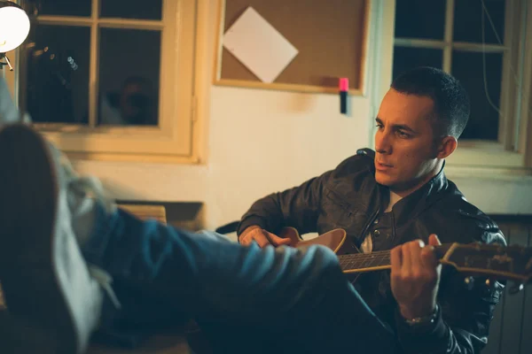 Uomo che suona la chitarra a casa dopo il lavoro — Foto Stock