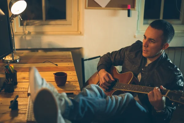 Man spelar gitarr hemma efter jobbet — Stockfoto